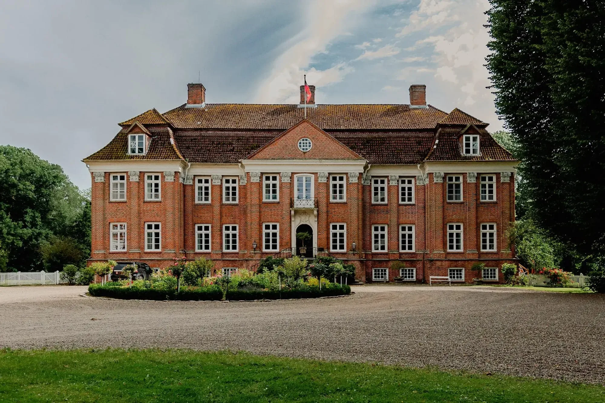 Das rote Herrenhaus von Gut Pronstorf hinter einer großen Rasenfläche